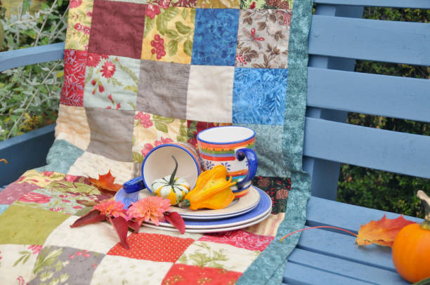 Backyard fall harvest decorations on sheltered patio swing bench with cozy blankets for cool autumn days and hot beverage