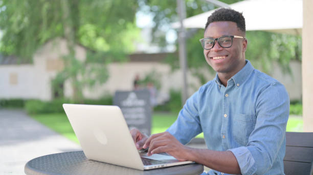 istock Young African Man with Laptop Smiling at Camera 1345714848