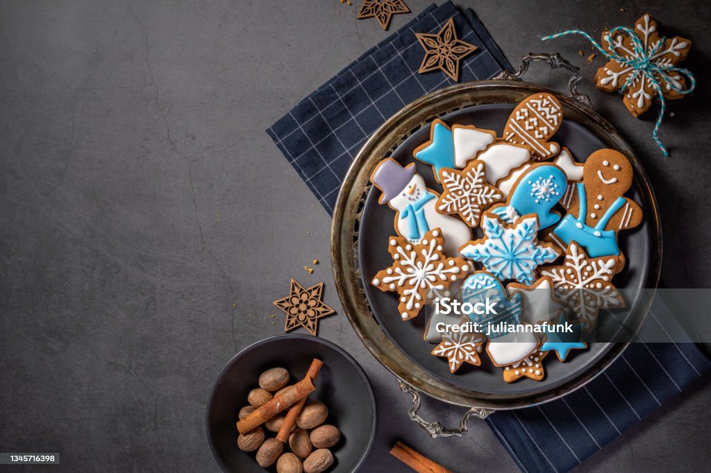 Decorated Gingerbread Christmas Cookies and spices Decorated Blue and White iced gingerbread Christmas cookies on rustic platter with spices. Dark Grey background. Top view with copyspace Cookie Stock Photo