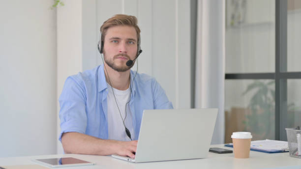 istock Creative Man with Headset and Laptop Looking at Camera 1345717184
