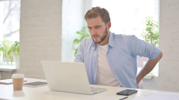 istock Young Creative Man having Back Pain in Modern Office 1345718386