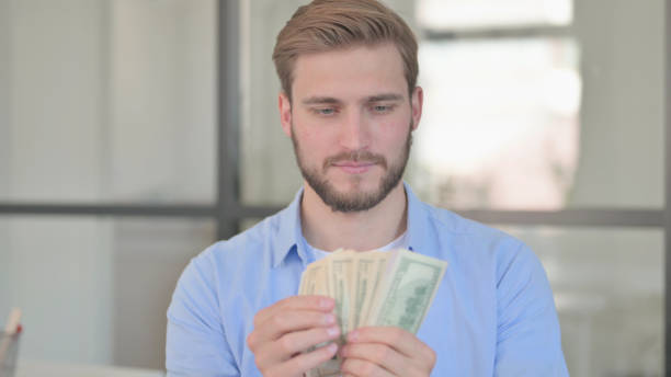istock Portrait of Young Creative Man Counting Dollars 1345718661