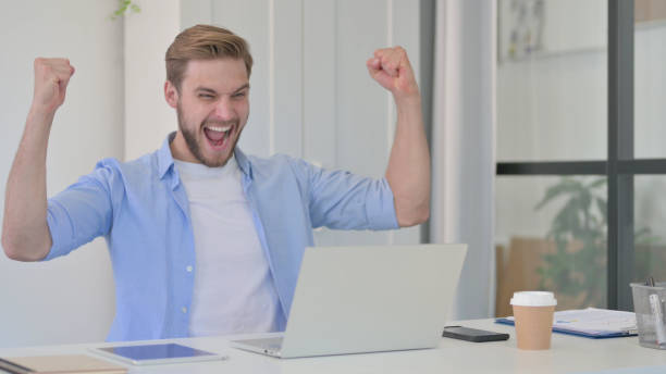 istock Successful Young Creative Man Celebrating on Laptop at Work 1345719586