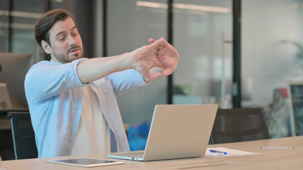 istock Tired Casual Young Man Stretching in Office 1345721815