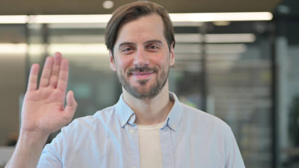 istock Hello by Casual Young Man Waving, Welcoming 1345721998