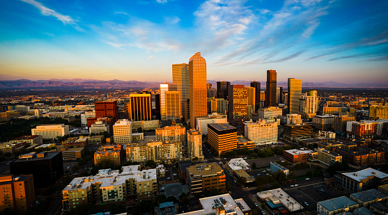 Alpine Glow Sunrise during an amazing golden hour dawn view of Denver , Colorado Cityscape Skyline as the Front Range of the Rocky Mountains glow with morning light and the Skyscrapers hit the gold