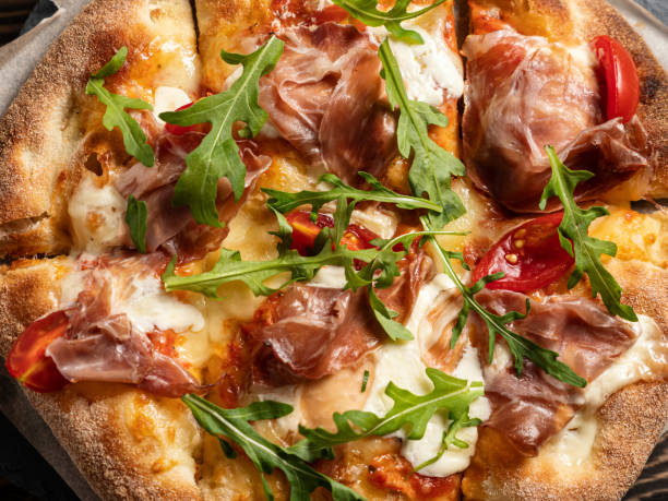 istock Prosciutto pizza with strachatella cheese, tomatoes and arugula leaves 1345723646