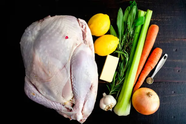 Whole turkey, butter, and aromatics on a wooden table