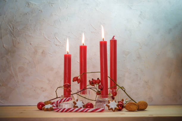 istock Four red candles, three are lit for the third Sunday before Christmas, Advent decoration on a wooden table against a rustic wall, copy space 1345735024