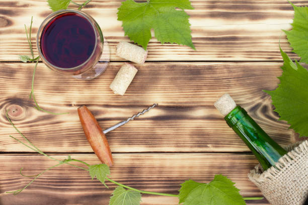 wine glass, corkscrew, corks, wine bottles, grapevine on rustic burnt wooden background. top view. copy space - cork tops imagens e fotografias de stock