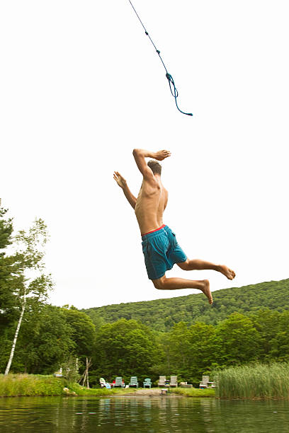 teenage boy balanceo de una cuerda en un lago - columpio de cuerda fotografías e imágenes de stock