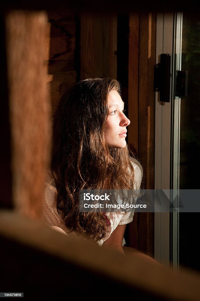 Teenage girl staring out of an open window Austerlitz,New York,USA, Looking Through Window Stock Photo