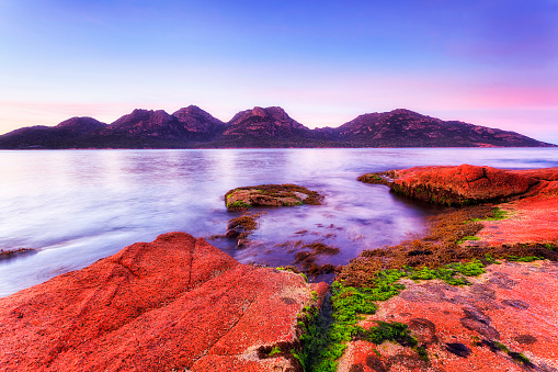 Freycinet national park on Freycinet peninsula of Tasmania Pacific coast across Coles bay at sunrise.