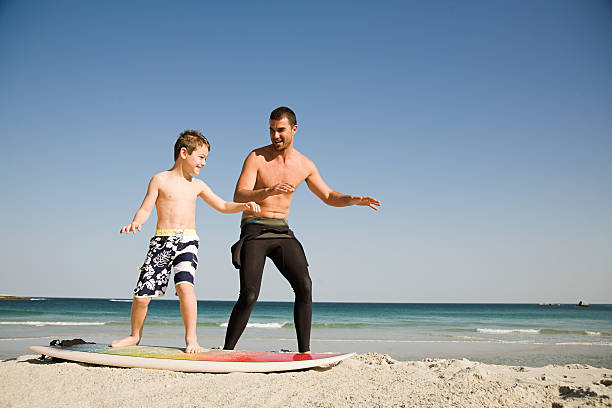 padre insegna figlio come surf - surfing beach family father foto e immagini stock