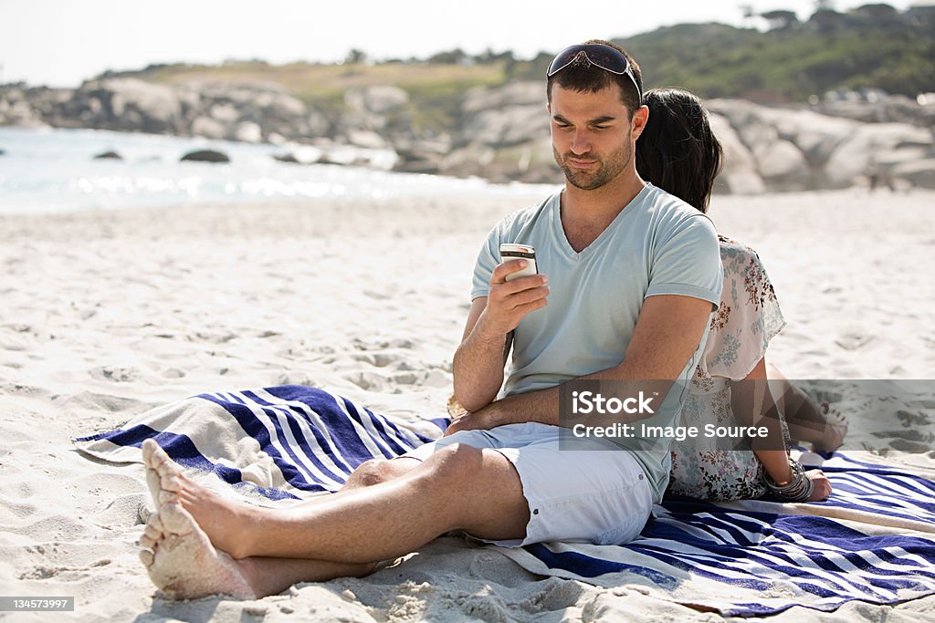 Young couple relaxing back to back on a beach Cape Town,South Africa, 25-29 Years Stock Photo