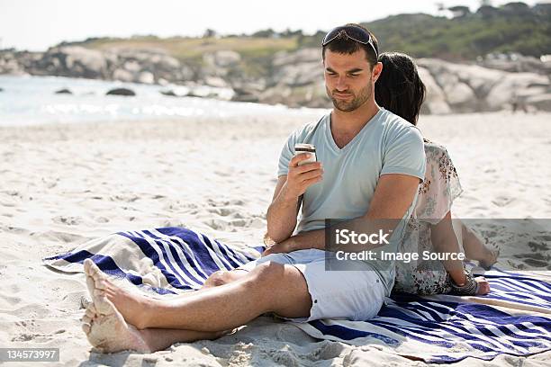 Young Couple Relaxing Back To Back On A Beach Stock Photo - Download Image Now - 25-29 Years, Adult, Adults Only