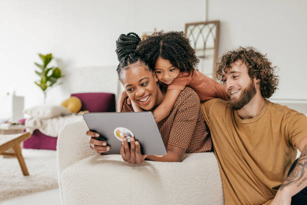 smiling parents and daughter at home watching online movie together - family stockfoto's en -beelden