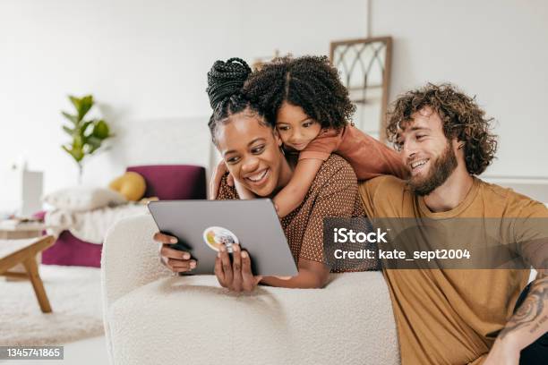 Smiling Parents And Daughter At Home Watching Online Movie Together Stock Photo - Download Image Now