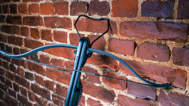 A modern compound crossbow handgun on the red brick wall background. Old weapon concept.