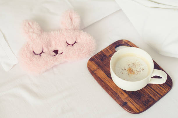 istock Cup of coffee with cute pink sleep mask 1345742691