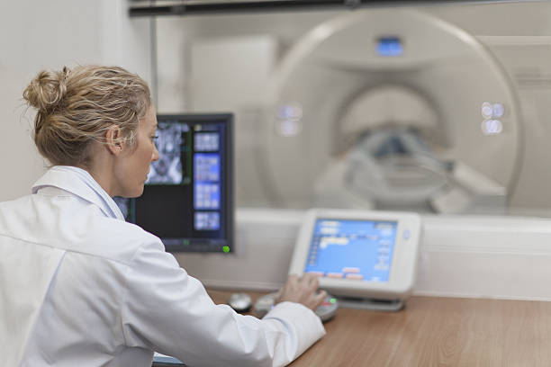 Doctor operating CT scanner in hospital  flat bed scanner stock pictures, royalty-free photos & images