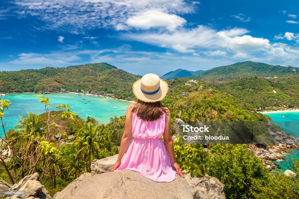 Woman and Aerial view of Koh Tao Woman traveler wearing pink dress and straw hat at viewpoint with Panoramic aerial view of Koh Tao island, Thailand Thailand Stock Photo