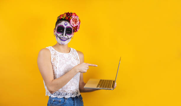 mexican catrina, portrait of young latin woman holding computer or laptop, halloween party in mexico - face paint human face mask carnival imagens e fotografias de stock