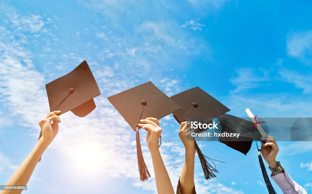 Vier Hände, die Abschlusshüte auf dem Hintergrund des blauen Himmels halten - Lizenzfrei Akademischer Abschluss Stock-Foto