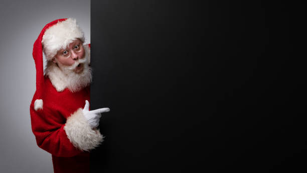 Santa Claus pointing black billboard stock photo