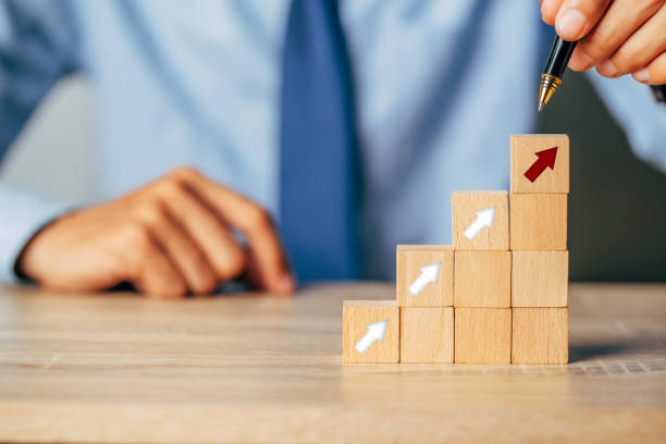 istock Hand arranging wood block stacking as step stair with arrow up.Ladder career path for business growth success process concept. 1345766293