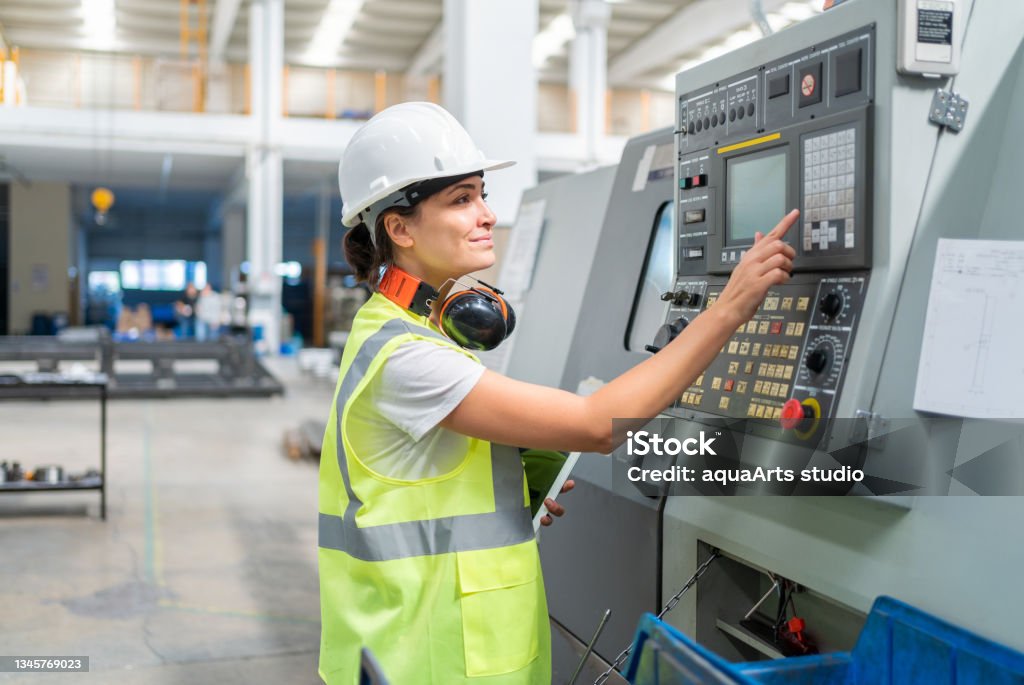 Female Engineer Programming A CNC Machine At Factory CNC Machine Stock Photo