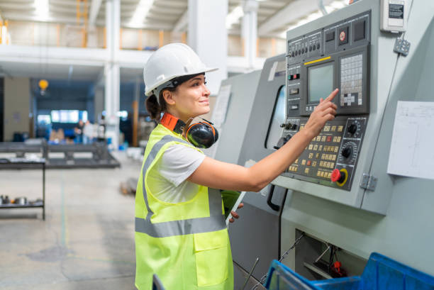 female engineer programming a cnc machine at factory - engineer occupation women industrial imagens e fotografias de stock