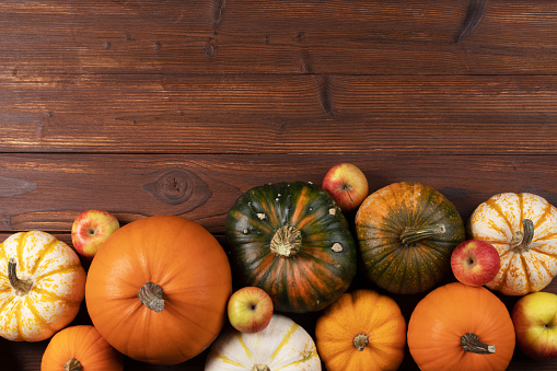 Fall border with pumpkins and apples. Top view on a rustic wood background with copy space for text