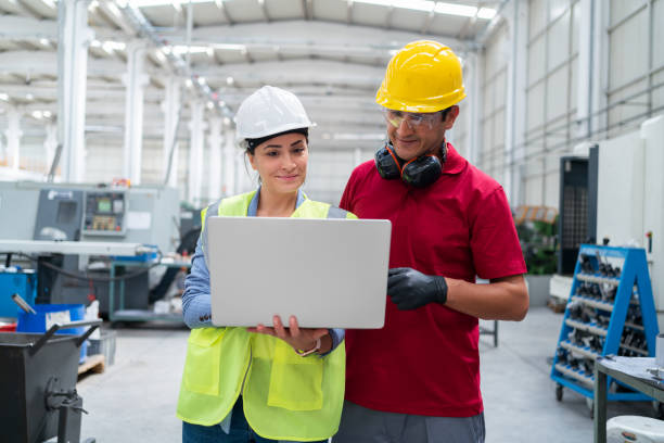 istock Female Engineer And Worker Discussing Production On Laptop Computer At Factory 1345771888