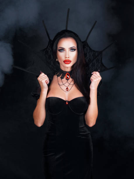 Beauty woman in Halloween vampire costume Beautiful young woman as sexy vampire in black dress with high collar and red gemstone jewelry - halloween portrait vampire woman stock pictures, royalty-free photos & images