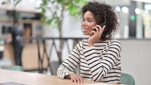 istock Cheerful African Woman Talking on Phone in Office 1345783696