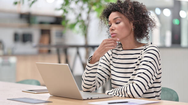 istock African Woman Thinking and Working on Laptop in Office 1345784350