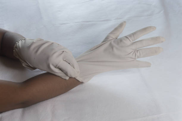 istock Hand Wearing Disposable Gloves against white background. High angle view. Close up. Use and protection of Hand Hygiene to reduce the risk of germs spreading due to hand contamination to the environment. 1345784403