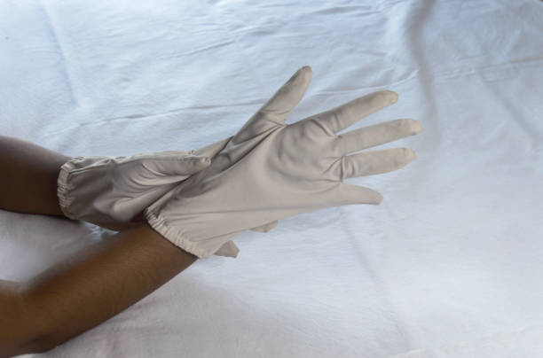 istock Hand Wearing Disposable Gloves against white background. High angle view. Close up. Use and protection of Hand Hygiene to reduce the risk of germs spreading due to hand contamination to the environment. 1345784419