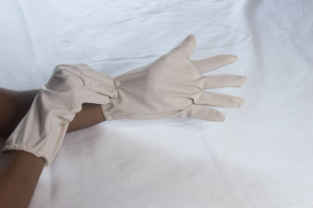 istock Hand Wearing Disposable Gloves against white background. High angle view. Close up. Use and protection of Hand Hygiene to reduce the risk of germs spreading due to hand contamination to the environment. 1345784430