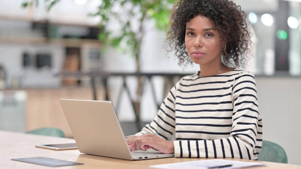 istock African Woman with Laptop Looking at Camera in Office 1345784445