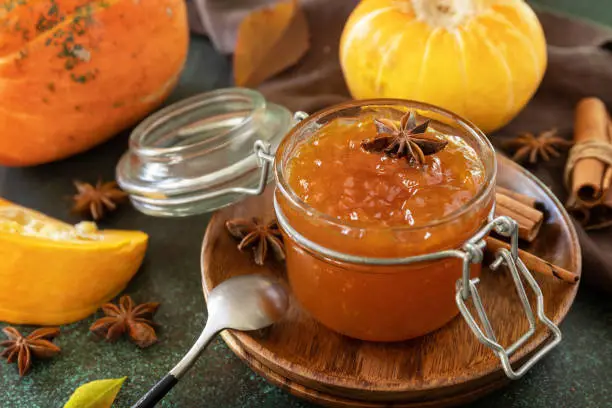 Homemade preserved, delicious sweet spicy sauce. Pumpkin confiture, jam, chutney sauce with spices on stone table.