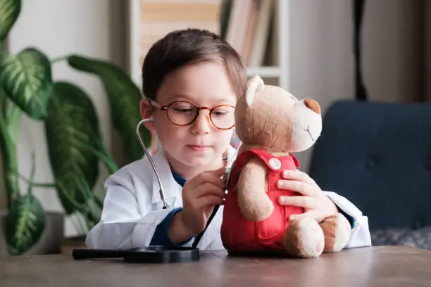 Adorable child wearing as doctor and examining his toy