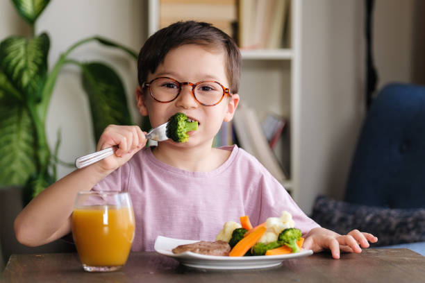 Child eating vegetables stock photo