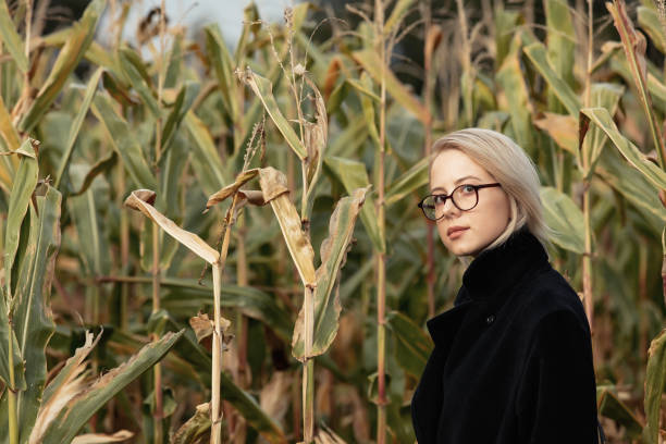 stylowa kobieta w czarnym płaszczu i szklankach na jesiennym polu kukurydzy - autumn clothing corn crop fashion zdjęcia i obrazy z banku zdjęć