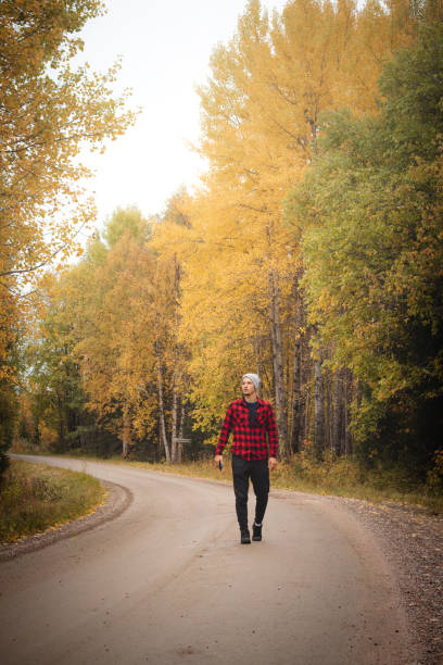 istock Man aged 23 wearing a checked red and black shirt walks along a foamy path surrounded by beautiful deciduous trees coloured in autumn colours. Enjoy the moment. Kainuu region, Finland 1345796933