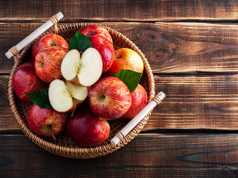 Fresh organic apples in a basket on a wooden background. Rustic. New Zealand gala variety. Copy space.