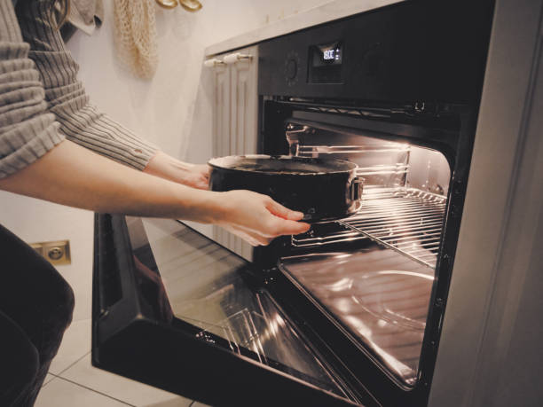 istock woman puts chocolate cake in the oven 1345801152