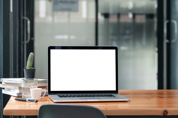 istock Mockup blank white screen laptop computer on wooden table in modern office room with copy space. 1345801487