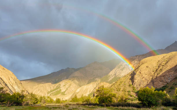 istock Bright full rainbow in the mountains against the dark sky 1345802181